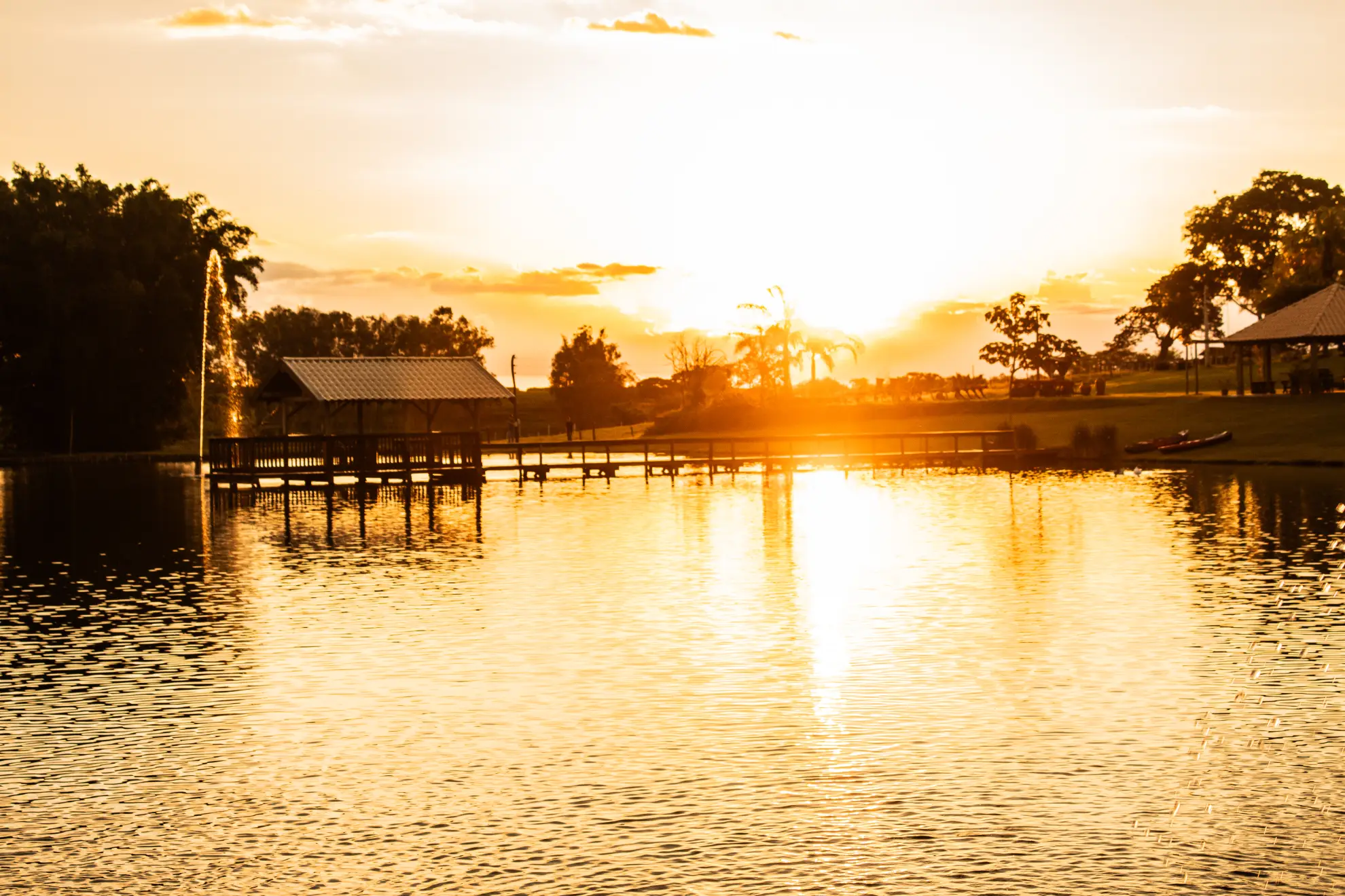 Lago ao pôr do sol com árvores ao fundo.